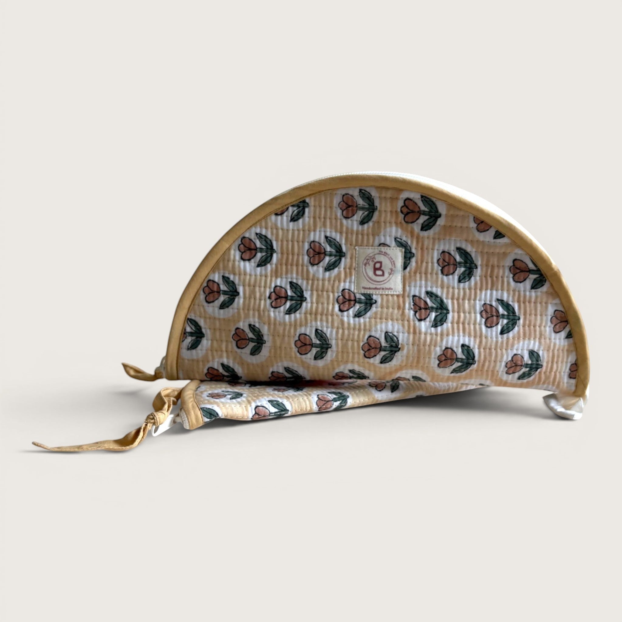 The Block & Bloom quilted makeup brush pouch in golden yellow with a rust tulip print and white oval frames.
