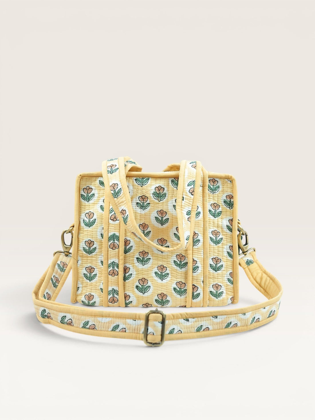 The Block & Bloom quilted mini tote in golden yellow with rust tulip block print, padded handles, and crossbody strap.