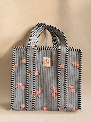 The Block & Bloom quilted mini tote in grey with pink whale print and black-and-white striped trim.