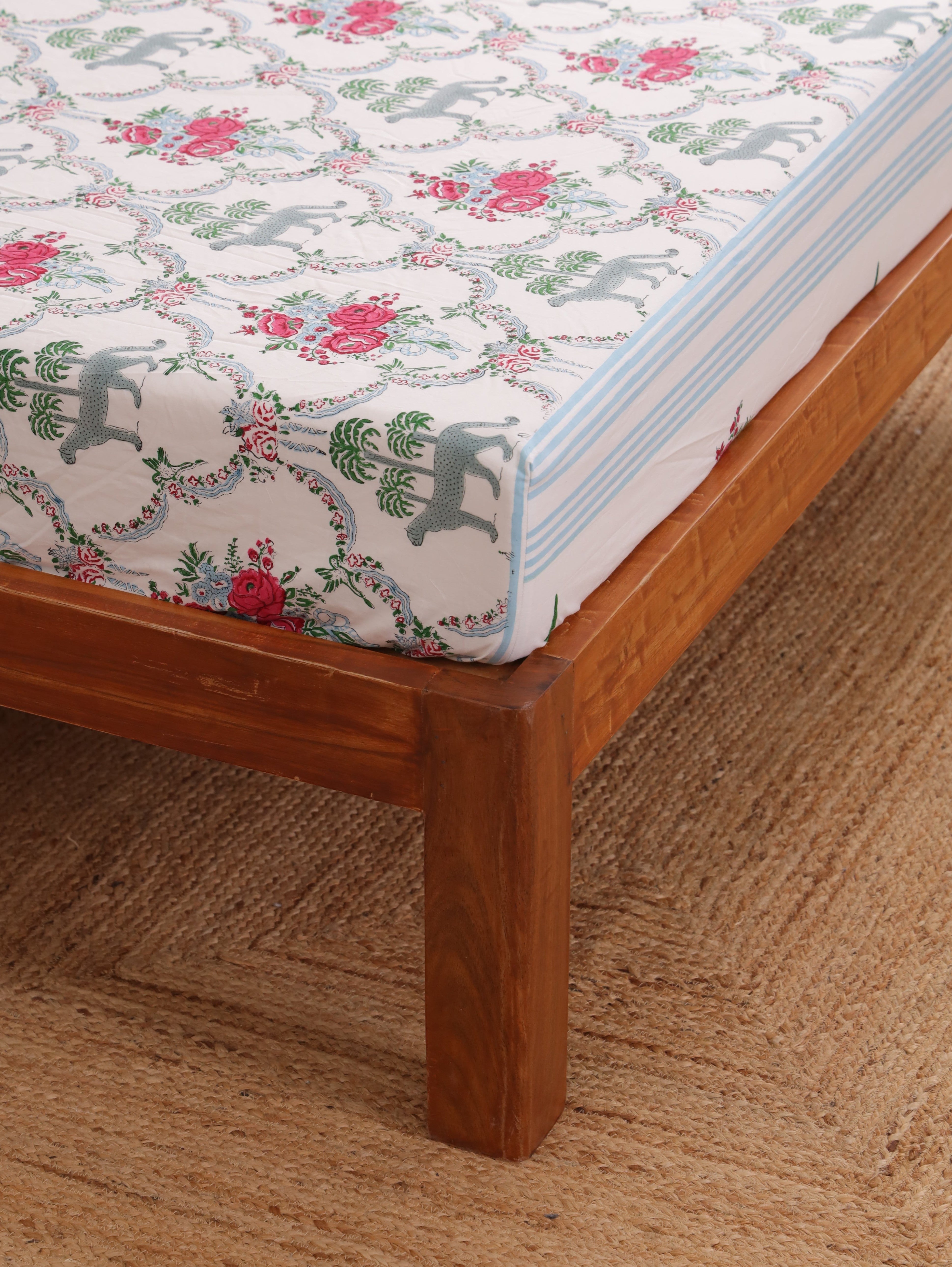 The Block & Bloom Royal Bagh fitted cotton sheet with cheetah, palm tree, and pink rose hand block print on white.