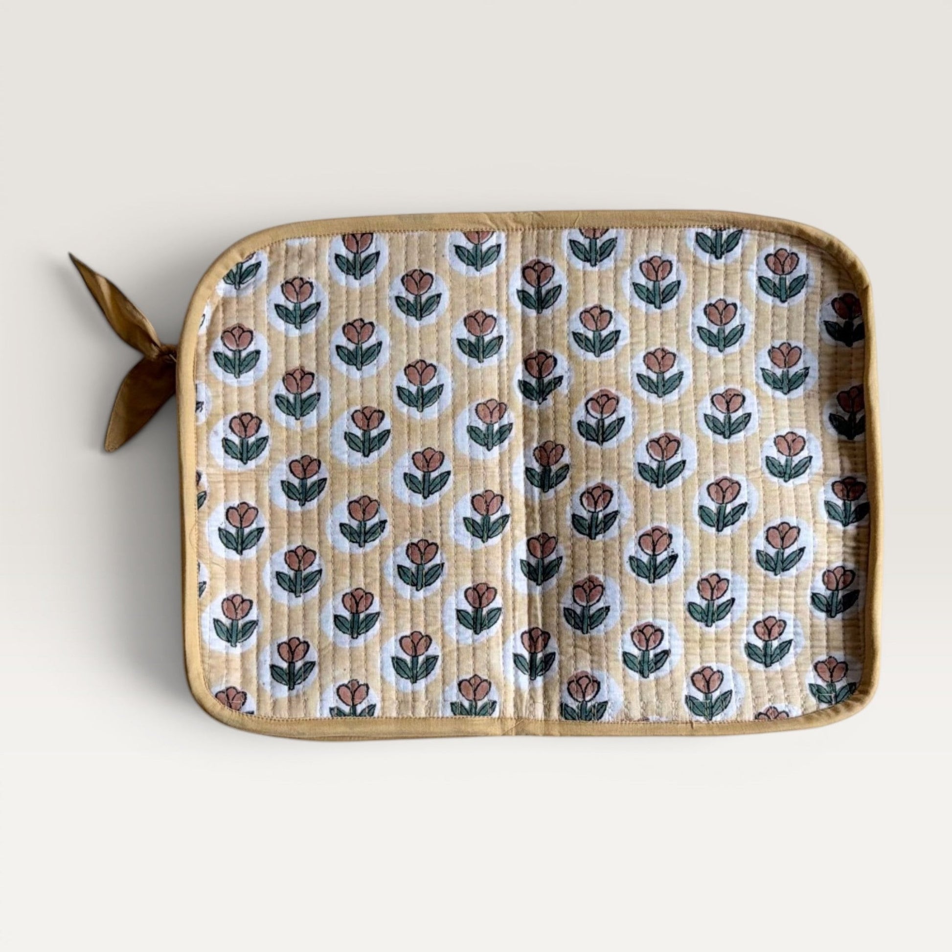 The Block & Bloom quilted laptop sleeve in golden yellow with a rust brown tulip block print and fabric bow zipper.