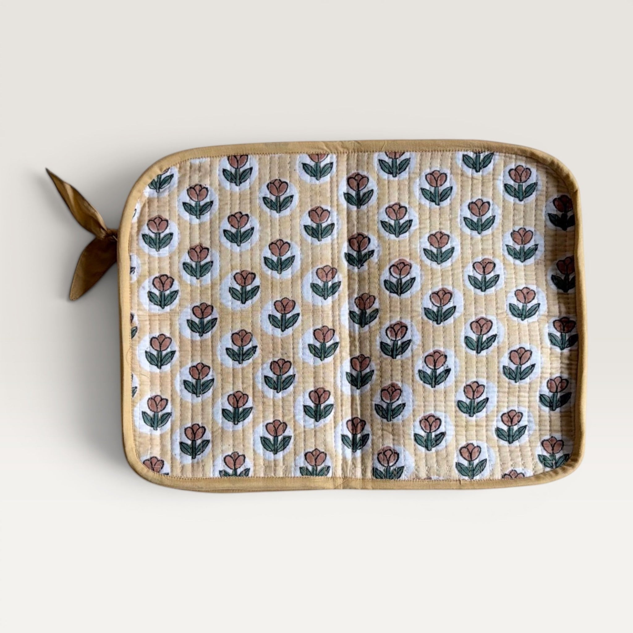 The Block & Bloom quilted laptop sleeve in golden yellow with a rust brown tulip block print and fabric bow zipper.