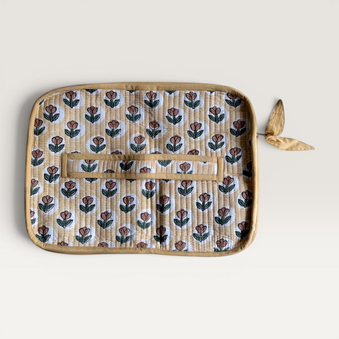 The Block & Bloom quilted laptop sleeve in yellow with rust tulip block print, featuring a YKK zipper and fabric bow.