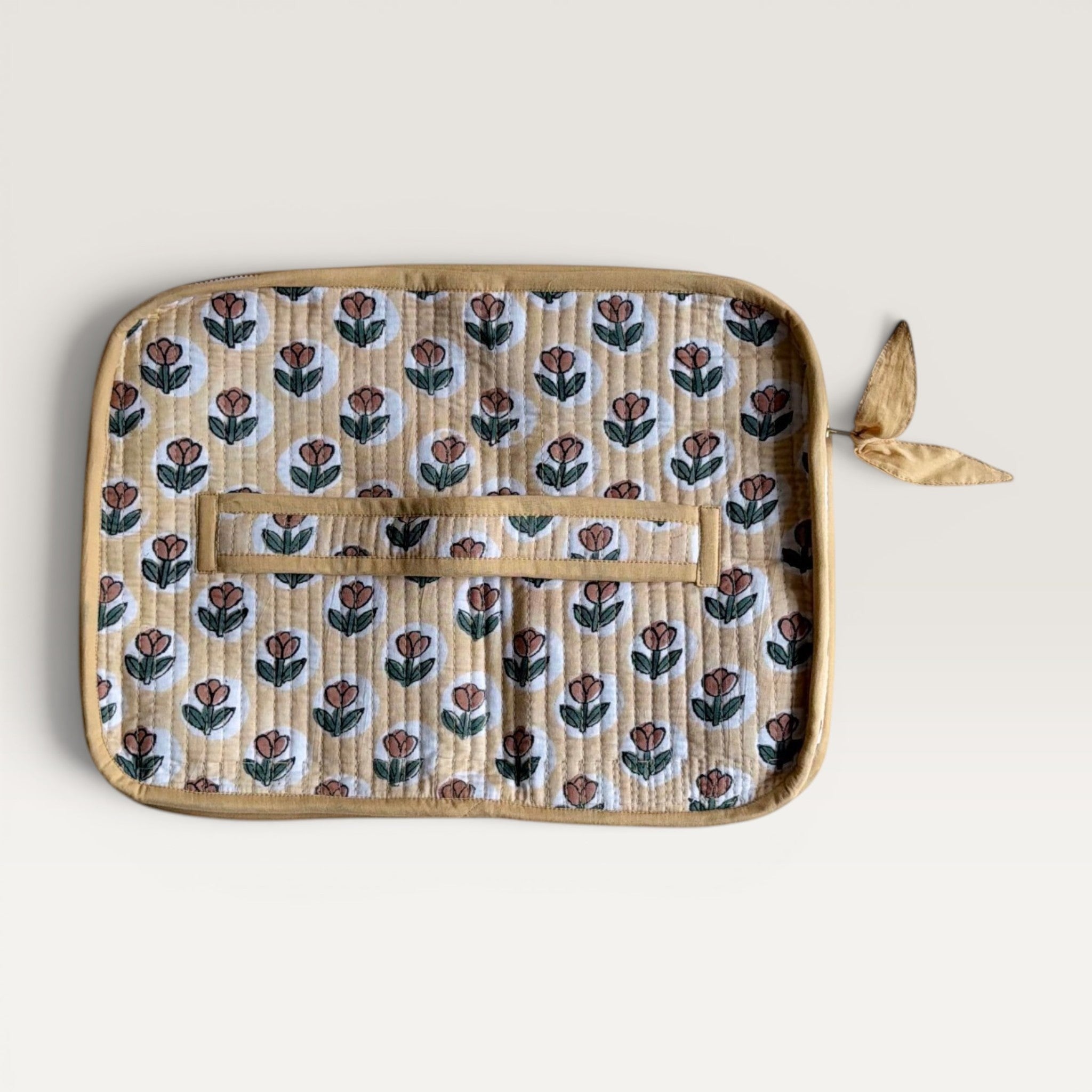 The Block & Bloom quilted laptop sleeve in golden yellow with rust tulip print and a hand-stitched fabric bow zipper.