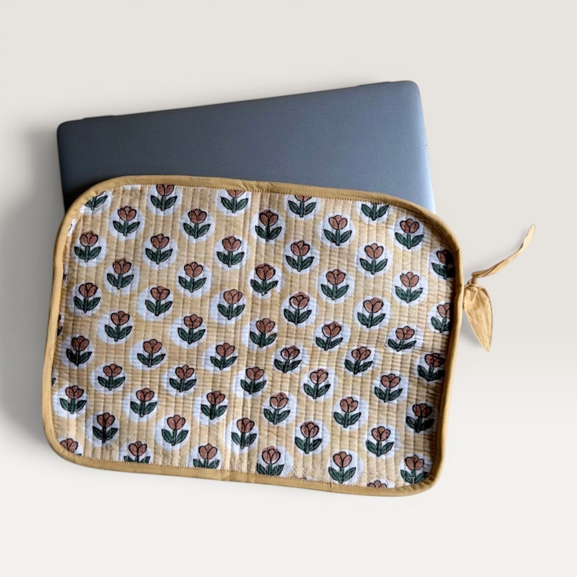 The Block & Bloom quilted laptop sleeve in yellow with rust tulip block print, featuring a YKK zipper and fabric bow.