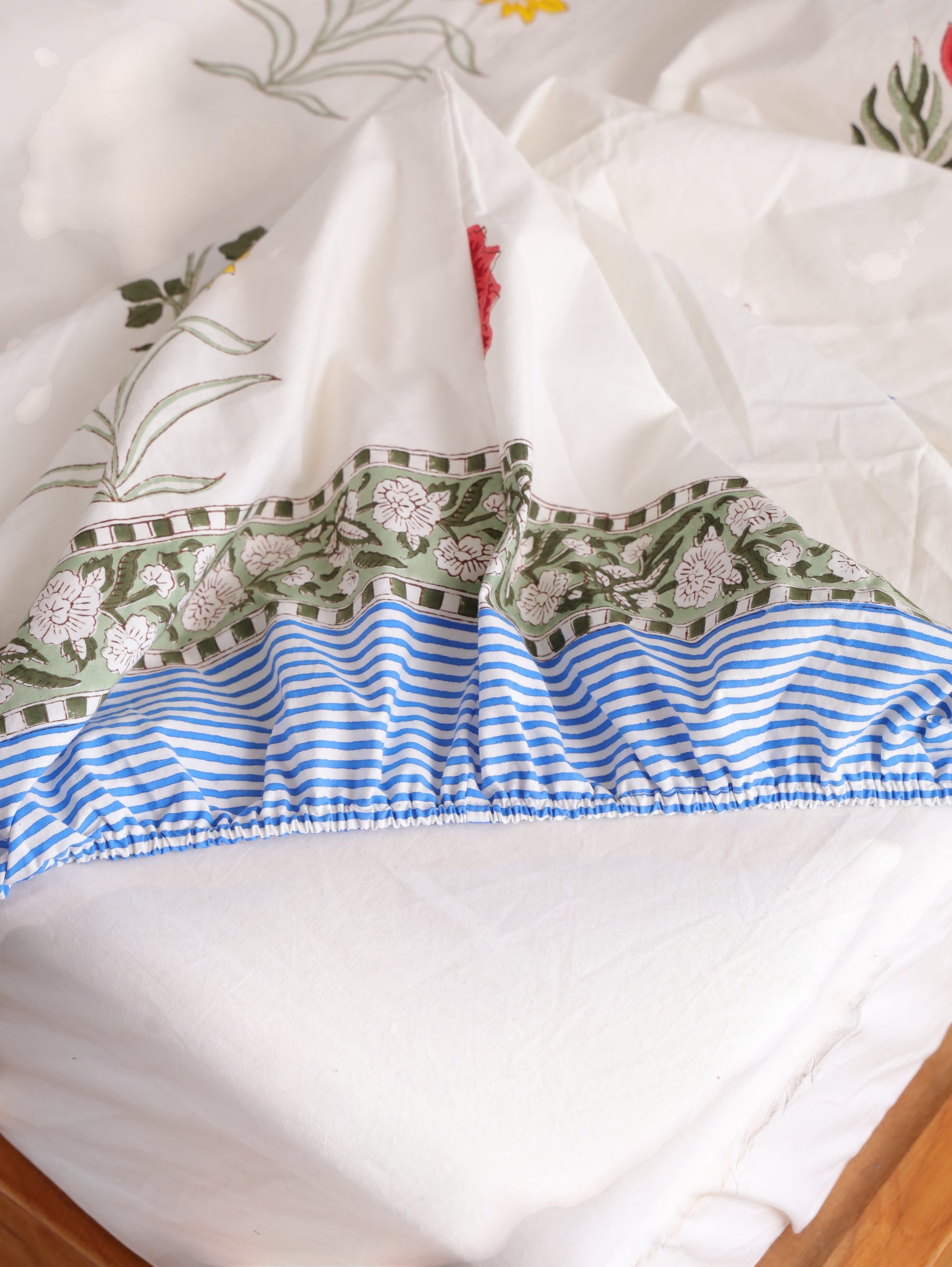 The Block & Bloom Wildflower Bagh fitted sheet in white cotton percale with floral print and blue striped elastic edge