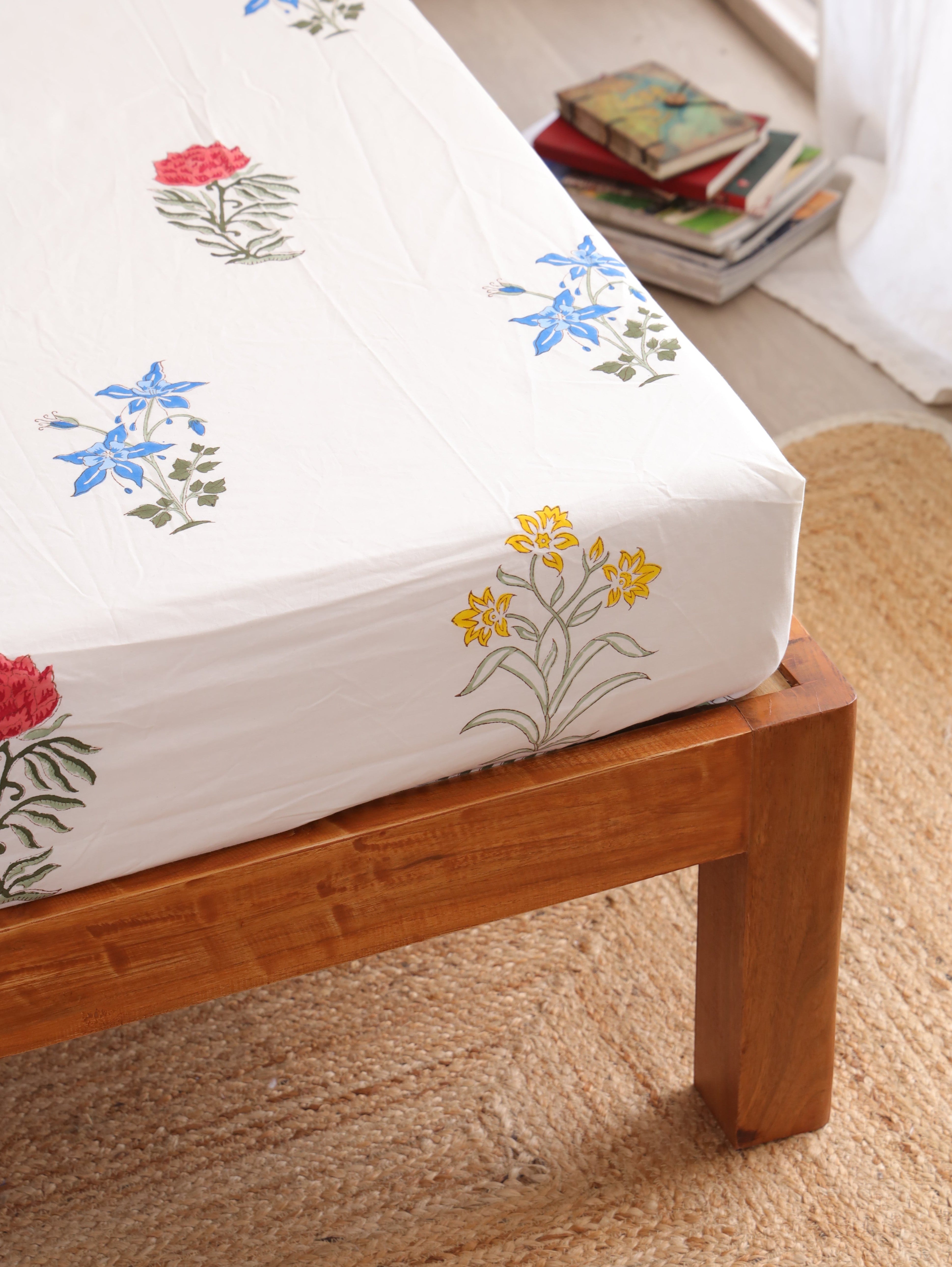 The Block & Bloom Wildflower Bagh cotton fitted sheet with blue, pink, and yellow floral block print on white fabric.